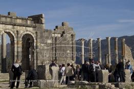 Image du Maroc Professionnelle de  Les touristes se rassemblent autour des arches de la basilique, le principal bâtiment administratif de Volubilis.
Le site de Volubilis est l'un des sites les mieux préservés au Maroc et le plus visité. La cité romaine se situe à proximité de Moulay Idriss Zerhoun à une trentaine de km au nord-ouest de Meknès, photo prise le jeudi 8 Mars 2012. Volubilis ville antique berbère Walili (Lauriers rose) qui date du 3e siècle avant J.-C. capitale du royaume de Maurétanie fondé comme seconde capital sous le règne de Juba II. (Photo / Abdeljalil Bounhar)
 